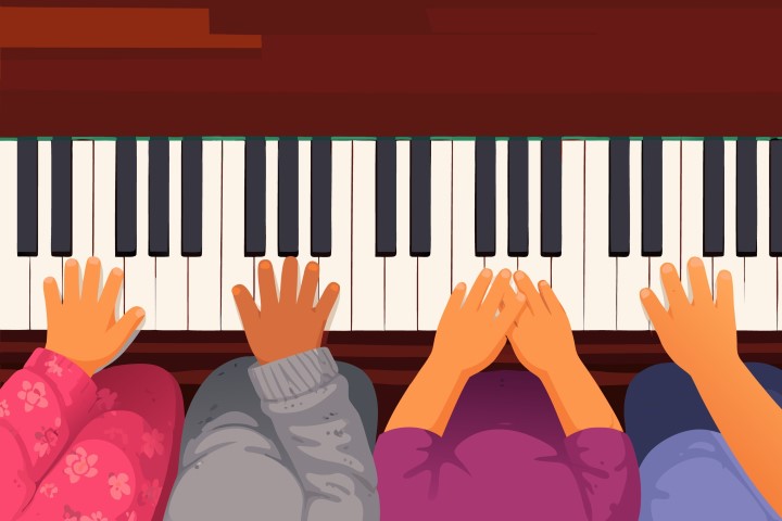 Hands of children playing piano together during a music lesson.